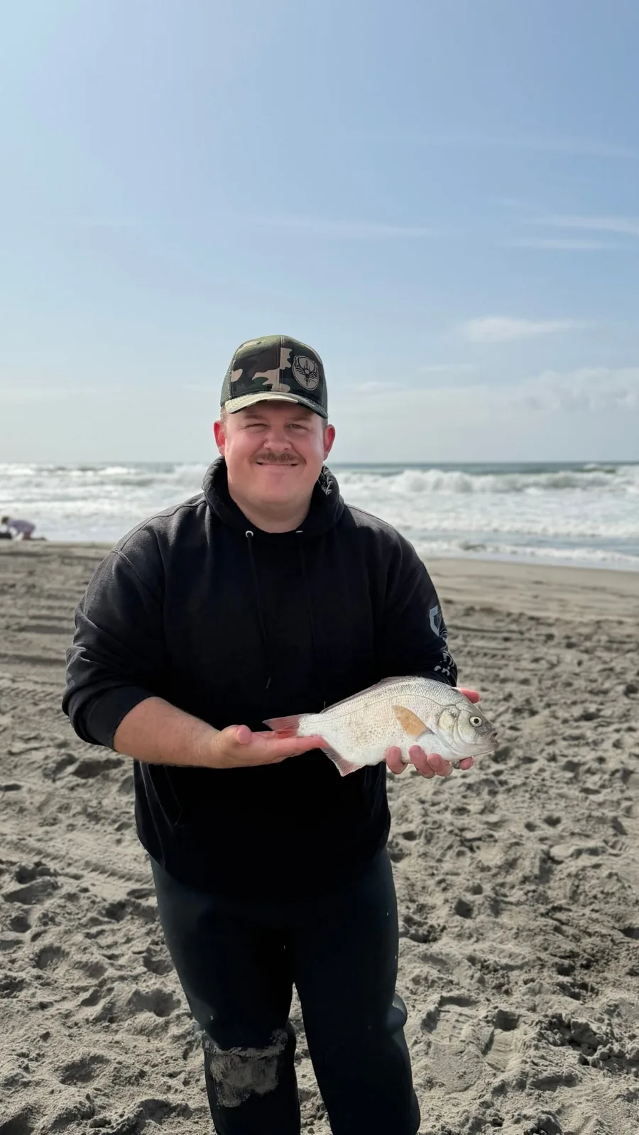 Adriel, founder of The Prep Verdict, standing on a beach in the Pacific Northwest holding a fish he caught
