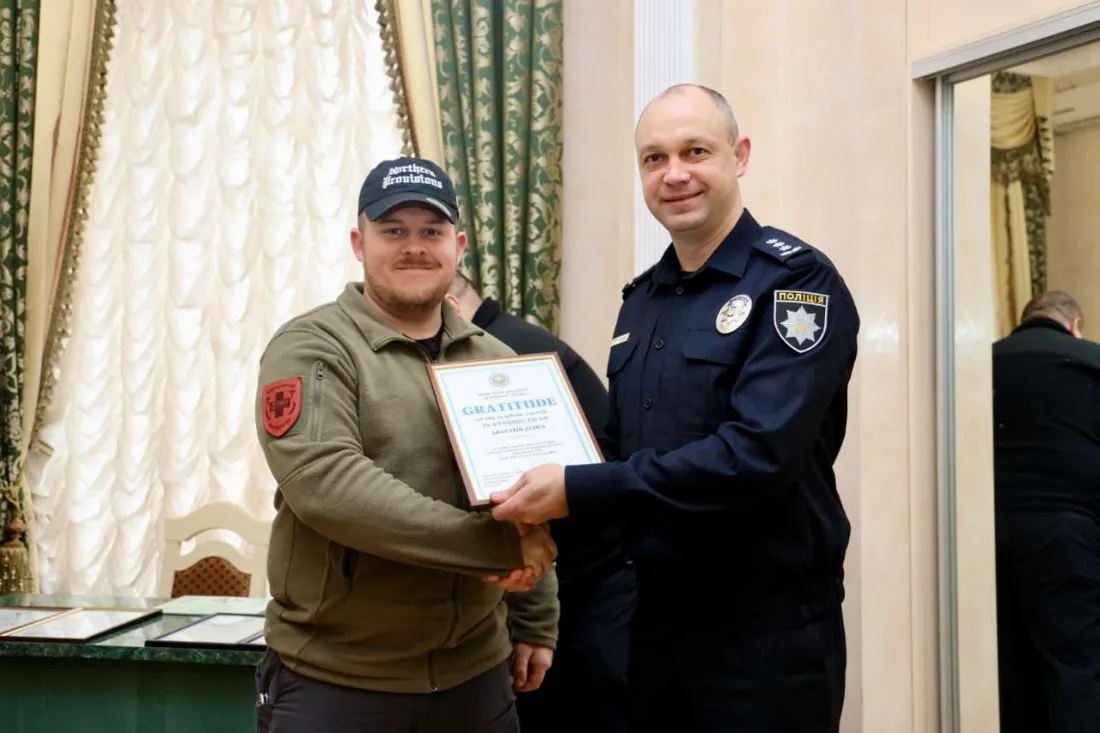 Adriel Stoltzfus receiving a certificate of gratitude from an officer of the National Police of Ukraine for medical instruction