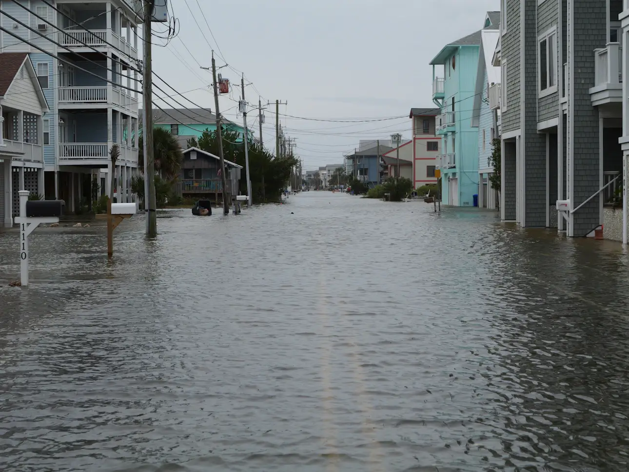 A residential coastal street flooded with storm surge water between houses during a king tide