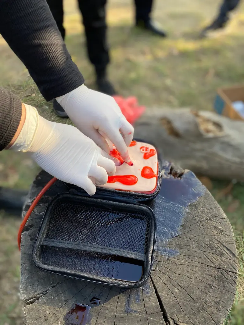 Gloved hands packing gauze into a simulated bleeding wound on a Stop the Bleed training pad